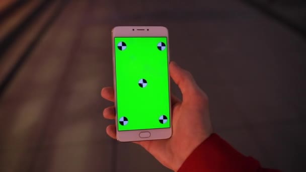 POV, порожній зелений екран смартфона в чоловічій руці, що йде в нічному місті — стокове відео