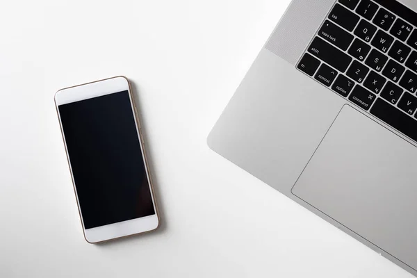 Pantalla de teléfono inteligente en blanco cerca del teclado portátil — Foto de Stock