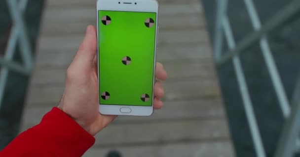 POV, mâle main tenant smartphone avec écran blanc marchant dans la jetée de la ville