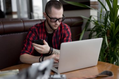 Kafede dizüstü bilgisayar ile çalışan şık adam freelancer