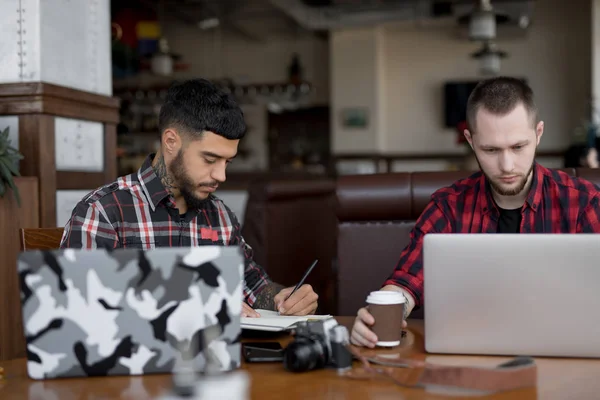 Молоді бізнесмени ведуть блог онлайн, працюючи з портативними комп'ютерами в кафе — стокове фото