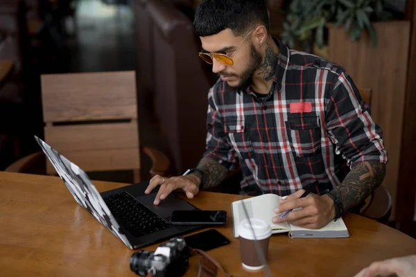 Stylish handsome man freelancer working by laptop computer in cafe