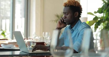 Kafede dizüstü bilgisayar kullanan Afro-Amerikan işadamı patronuna telefonla danışın