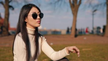 Asya kadın oturan içinde bir park ile gözlük