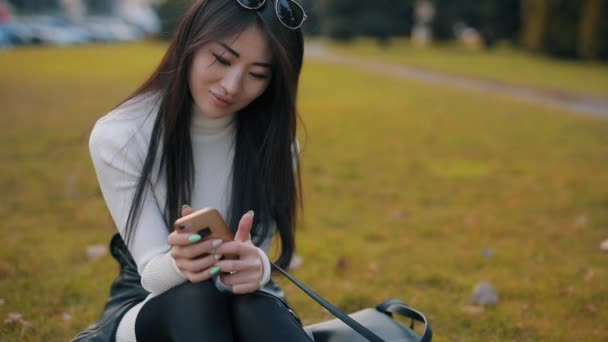 Asiatin nutzt Anwendung in Smartphone-Outdoor — Stockvideo