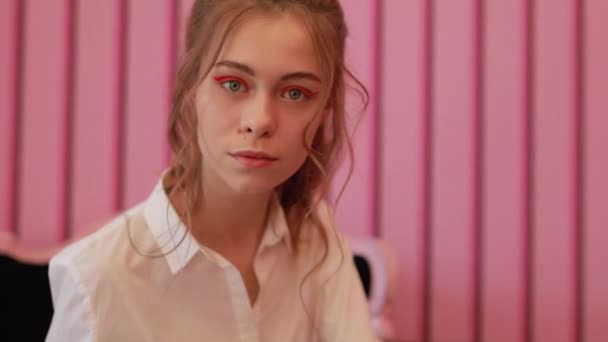 Νεαρό μοντέλο που ποζάρει στην καρέκλα σε ροζ στούντιο — Αρχείο Βίντεο