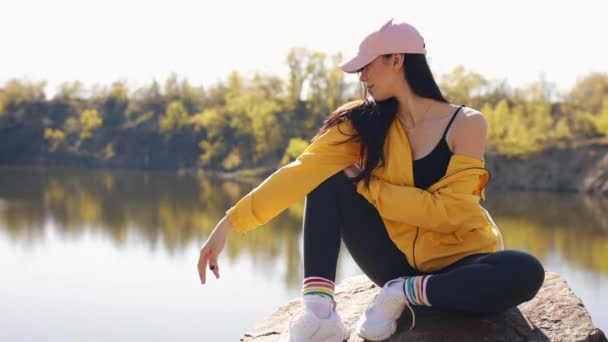 Женщина-туристка в желтой куртке наслаждается отдыхом на природе — стоковое видео
