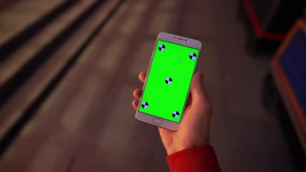 POV, блеск зеленого экрана смартфона в мужской руке, гуляющей по ночному городу — стоковое видео