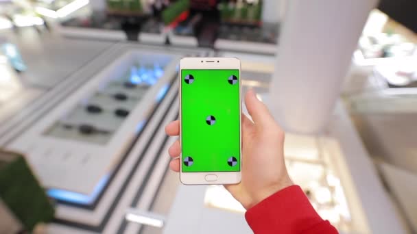 Вид от 1-го лица, используя чистый зеленый экран смартфона в торговом центре, макет — стоковое видео