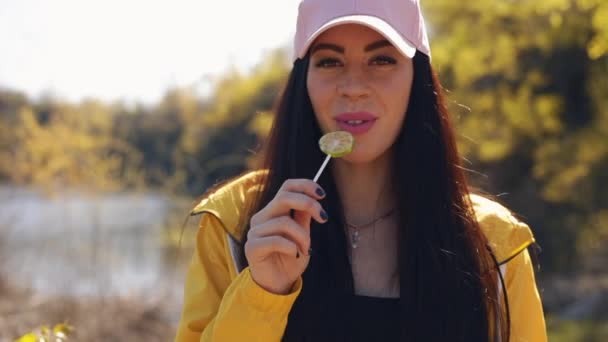 Сексуальная женщина ест конфеты на природе — стоковое видео
