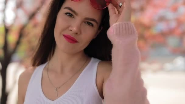 Jolie femme en lunettes roses marchant dans un parc — Video