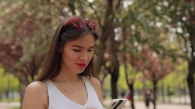 Yaz parkında akıllı telefondan mesaj okuyan bir kadın.