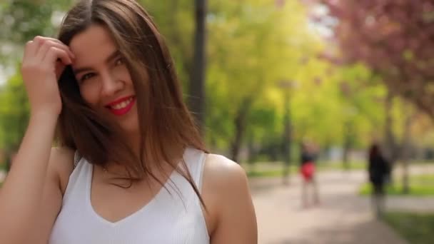 Mulher morena bonita com lábios cor de rosa andando em um parque — Vídeo de Stock