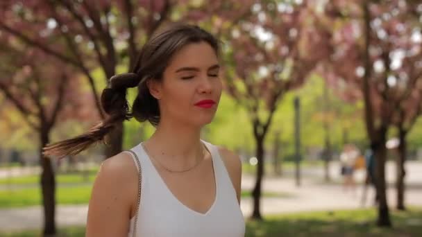 Bella donna bruna con labbra rosa che cammina in un parco — Video Stock