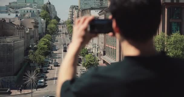 Zadní pohled na neidentifikovatelného muže, který fotografuje ve městě smartphone — Stock video