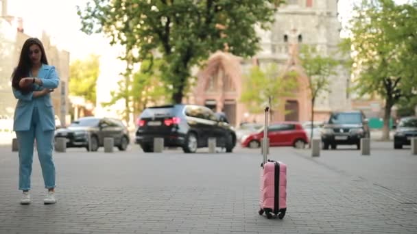 Distraherad glömsk kvinna väntar taxi i staden och glömmer resväska — Stockvideo