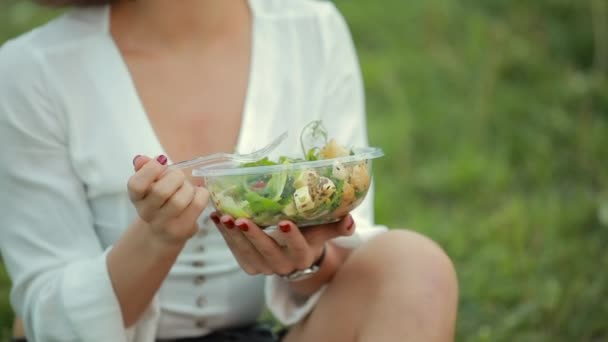 Piękna kobieta jedzenia Sałatka siedzi na trawie — Wideo stockowe