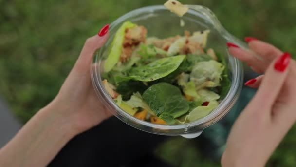 Жінка їсть салат сидить на траві — стокове відео