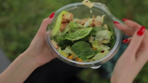 Vrouw eet salade zittend op gras — Stockvideo