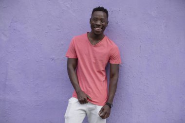 Menekşe duvarında boş yaşayan mercan t-shirt poz Afrikalı Amerikan adam modeli gülümseyen