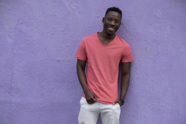 Menekşe duvarında boş yaşayan mercan t-shirt poz Afrikalı Amerikan adam modeli gülümseyen