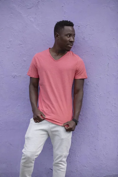 Афроамериканець людина модель постановки в порожньому життя коралових футболку на фіолетову стіну — стокове фото