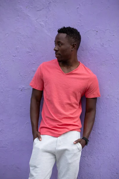 Afro-americano homem modelo posando no vazio vivo coral t-shirt no violeta parede — Fotografia de Stock