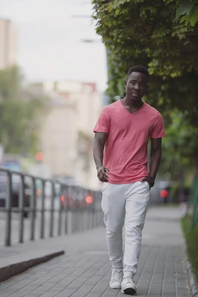 都市を歩く生きているサンゴのTシャツでアフリカ系アメリカ人の男性 — ストック写真