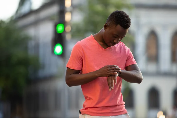 Afro-amerikai férfi élő korall t-shirt keres időt a városban — Stock Fotó