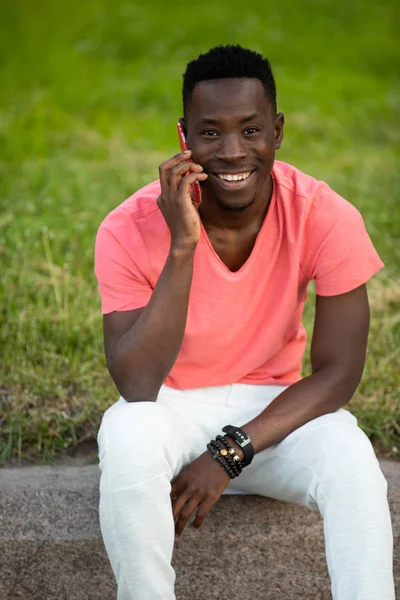 Akıllı Telefonda konuşan yaşayan mercan t-shirt Afrikalı Amerikalı adam — Stok fotoğraf