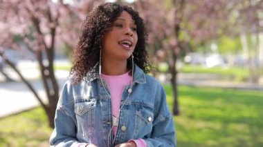 İlkbaharda bir parkta müzik dinleyen çok ırklı kadın