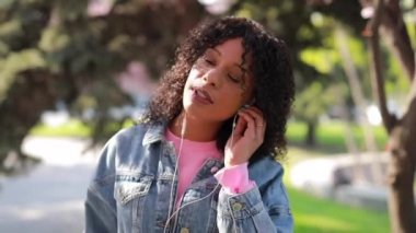 İlkbaharda bir parkta müzik dinleyen çok ırklı kadın