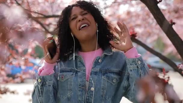 Multiraciale vrouw luisteren naar muziek in een park in de lente — Stockvideo