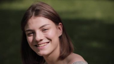 Parkta gülümseyen mutlu genç kadının portresi