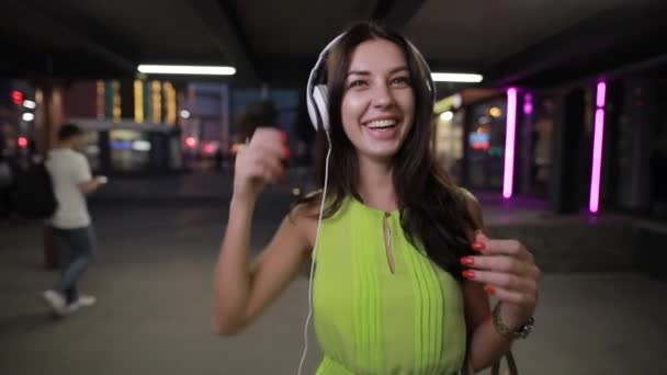 Vrouw in hoofdtelefoon 's nachts stad — Stockvideo