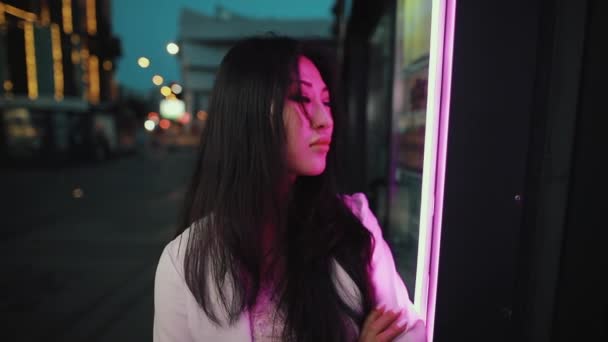 Портрет азиатки в ночном городе в фиолетовом свете — стоковое видео