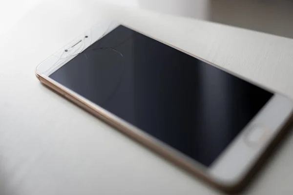 Kraschade skärm av smartphone på ett bord — Stockfoto