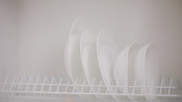 Мужская рука положила чистые тарелки в шкаф полки — стоковое видео