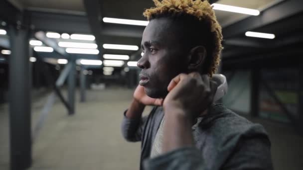 Hombre afroamericano con auriculares en la noche túnel subterráneo — Vídeos de Stock