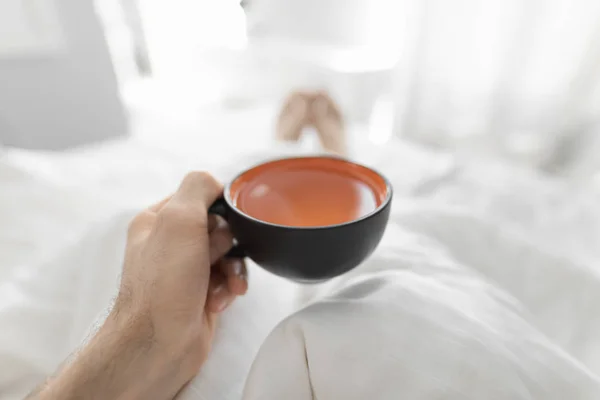 Вид з першої особи, п'є ранковий чай у ліжку — стокове фото
