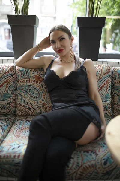 Seksikäs nainen muotokuva istuu kahvilassa sohvalla — kuvapankkivalokuva