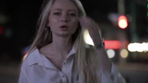 Блондинка-модель позирует с длинными волосами в ночном городе — стоковое видео