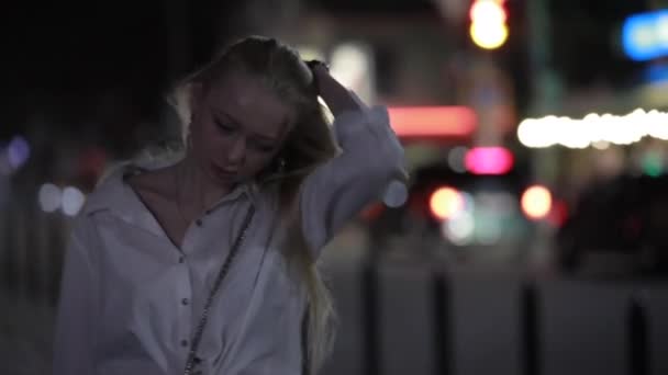 Блондинка-модель позирует с длинными волосами в ночном городе — стоковое видео