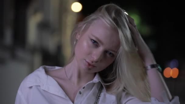 Jolie mannequin blonde posant toucher les cheveux longs dans la ville de nuit — Video