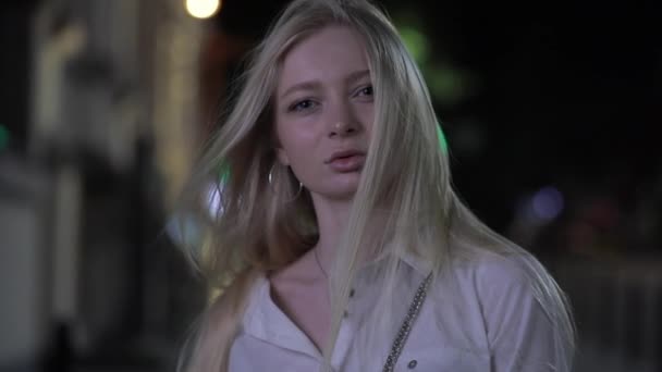 Pretty blonde model posing touching long hair in night city — Stock Video