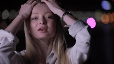 Seksi sarışın kadın gece şehirde uzun saç dokunmadan poz