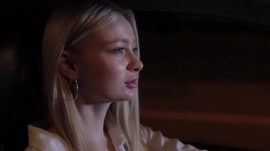 Gece arabada oturan kadın sürücü pencereye bakıyor