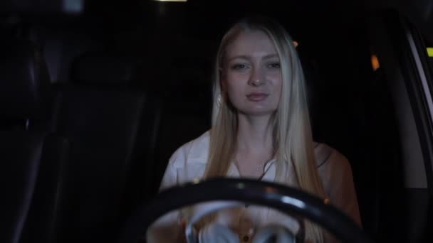 Kadın sürücü gece şehirde arabada kulaklık giymek — Stok video