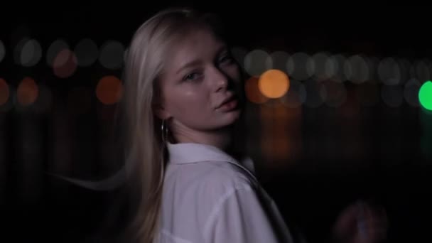 Красива блондинка модель з довгим волоссям позує в нічному місті — стокове відео