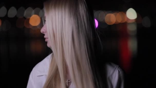 Красива блондинка обертається обличчям в нічному місті — стокове відео